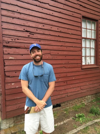 Alex in front of a bullet-riddled wall